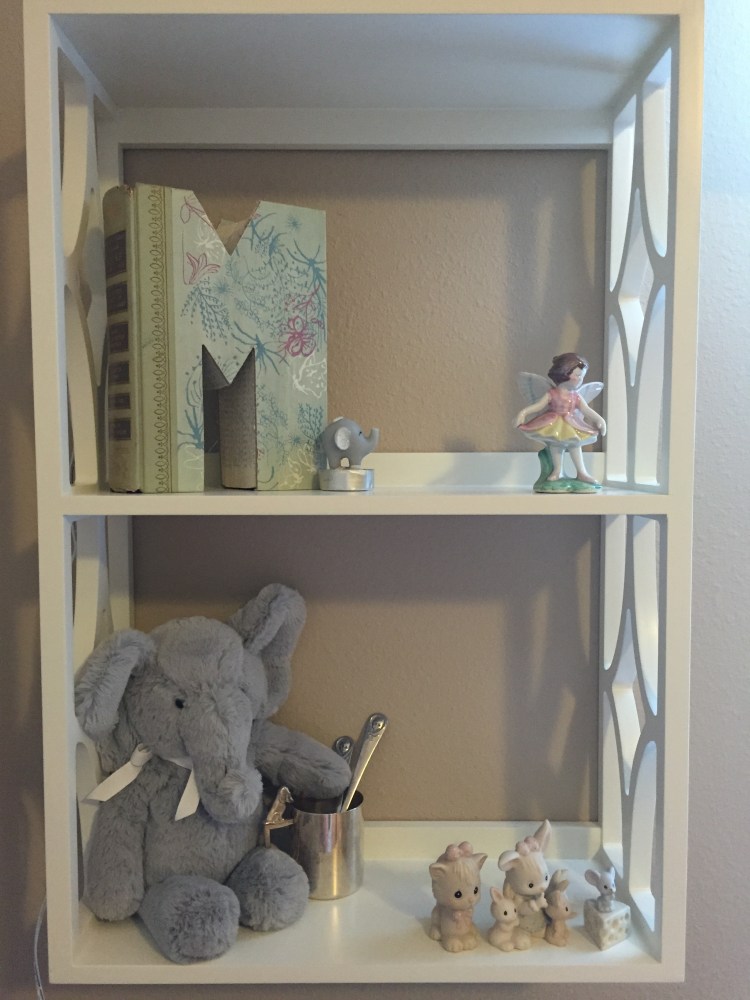 The shelves are decorated with sentimental trinkets. The "M" is made out of a book and is a souvenir I bought when Troy and I went on our "babymoon" to St. Augustine in October. The fairy is a gift that my mom bought for my maternal grandmother years ago. My grandma gave it to me a couple years ago. The stuffed elephant is holding onto a silver cup that holds some of Troy's baby spoons. And the Precious Moments figurines are mine from when I was a child. 