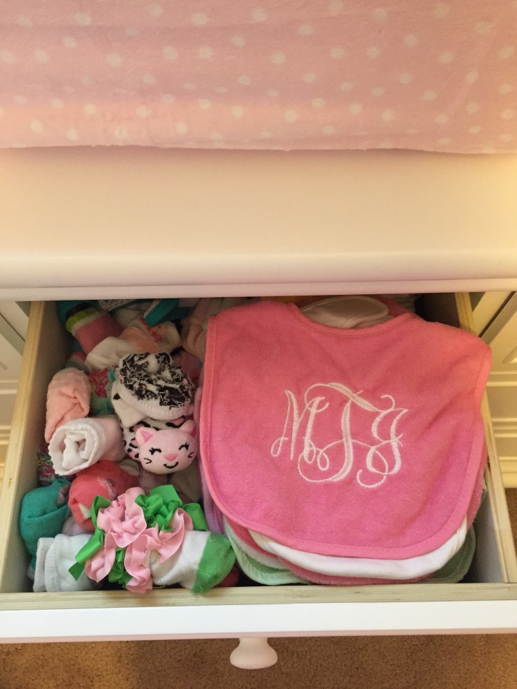 A dresser drawer filled with cute socks and bibs.